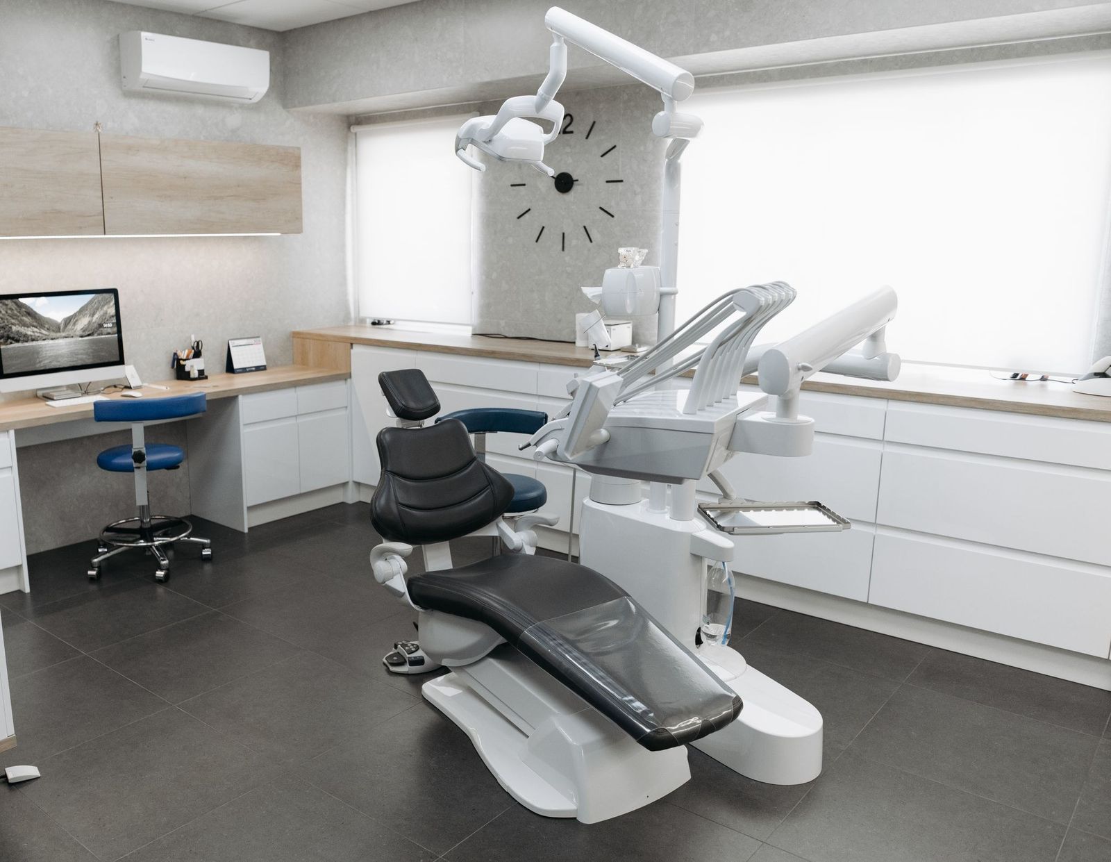 Dental treatment room with a wall clock and light wood cabinets